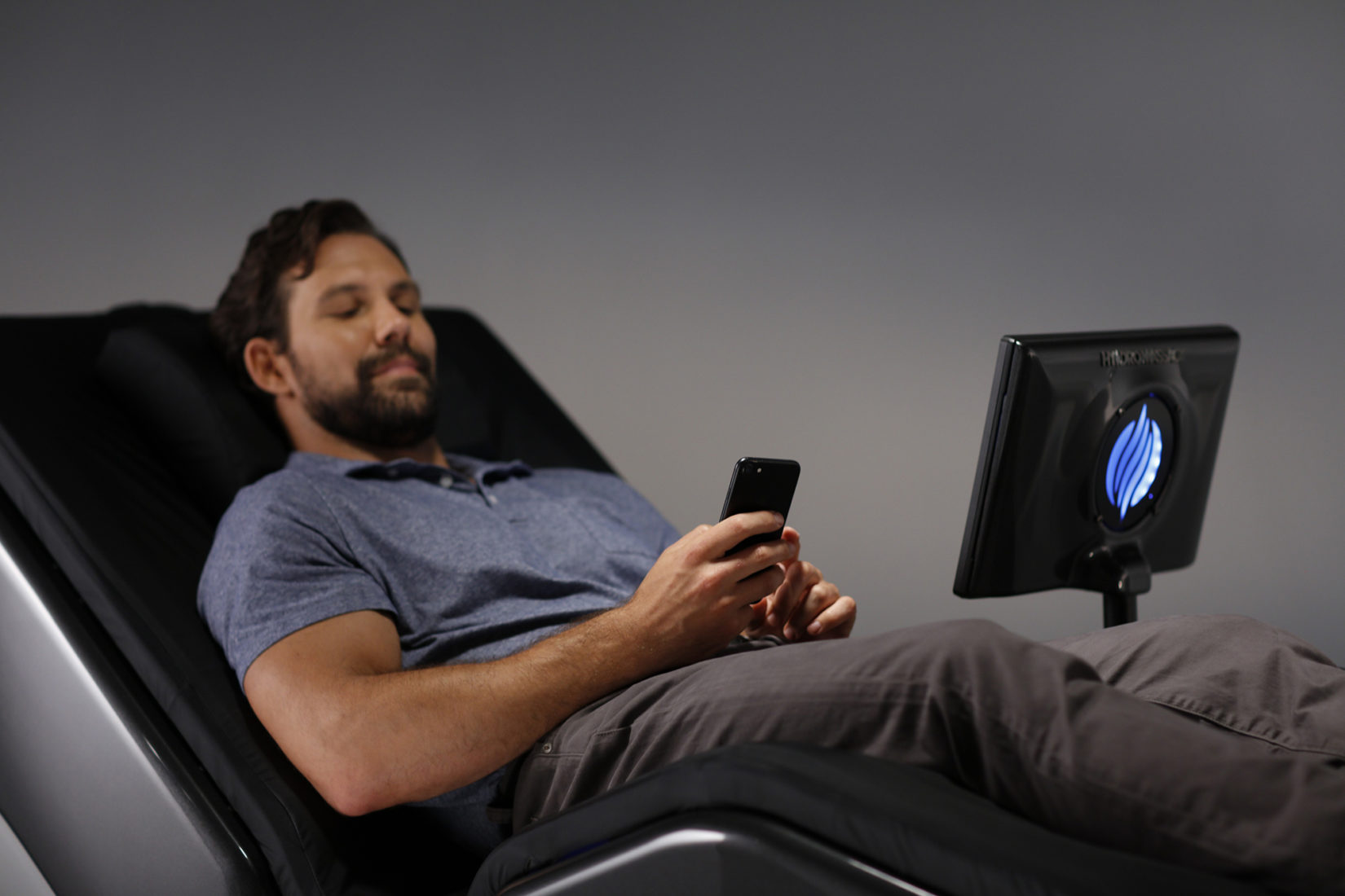 Man relaxing and working on his phone while using a HydroMassage Lounge 440X