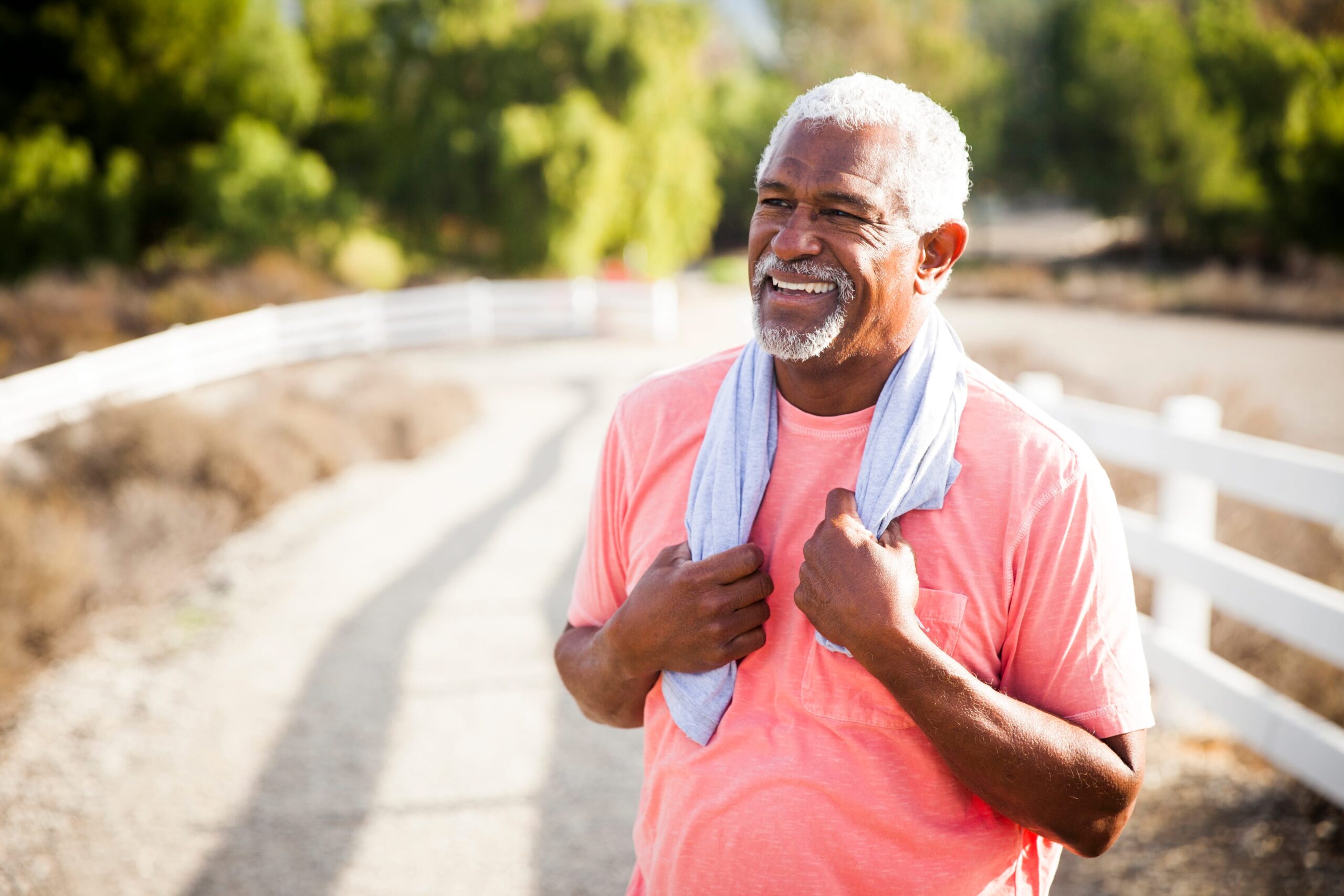 Older man standing outside with a towel after a workout, getting muscle pain relief for back pain